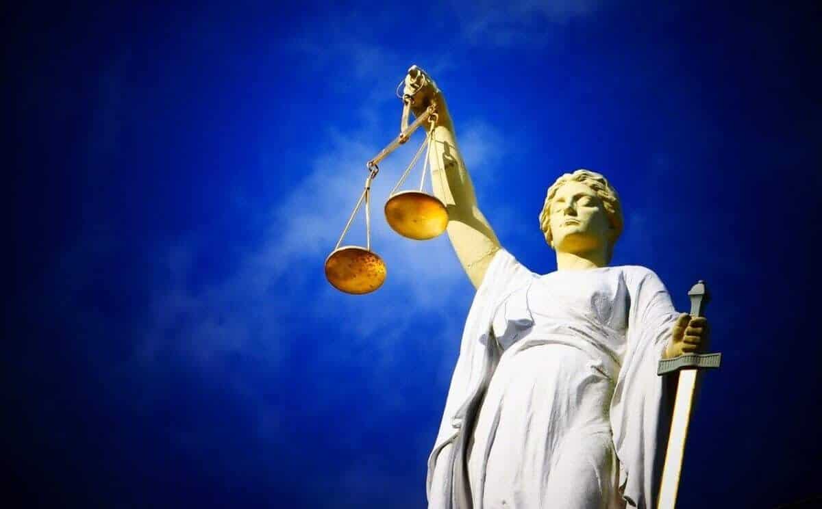 Statue of lady of justice holding scales against a blue sky