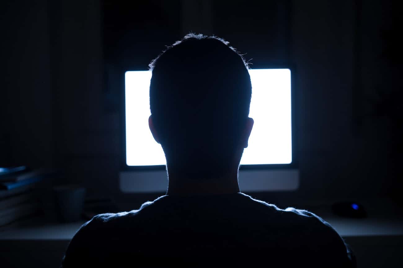 Silueta de la cabeza del hombre delante del monitor de la computadora por la noche
