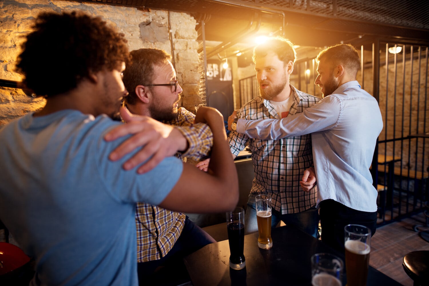 Friends preventing fighting of two angry guys in a bar