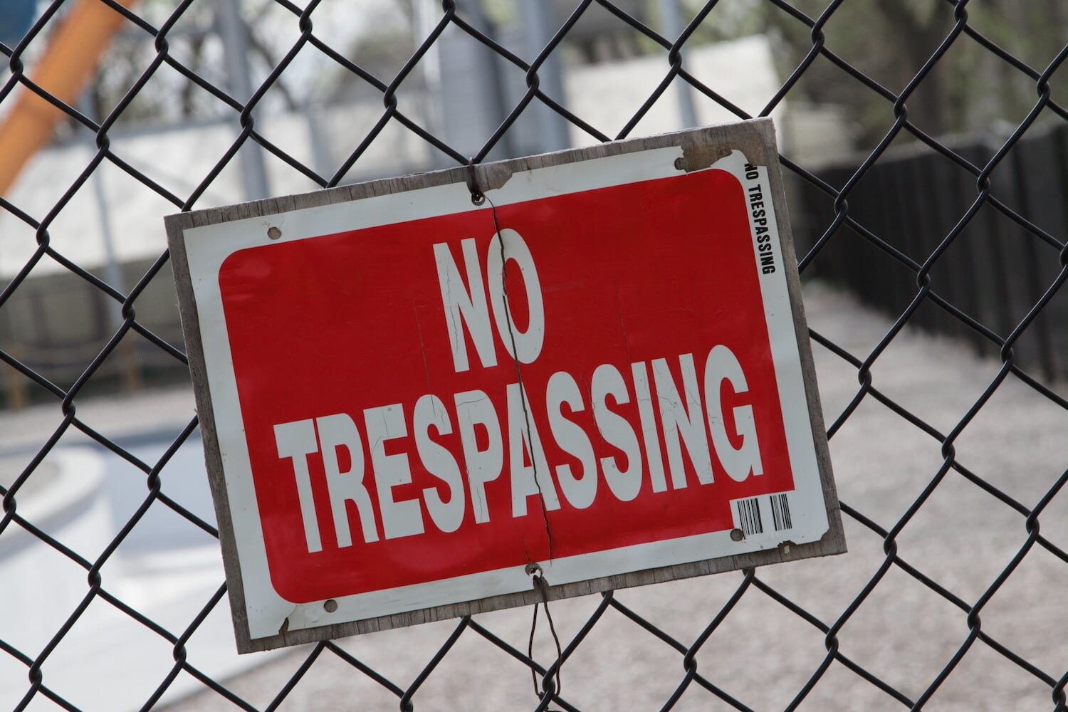 Red "No Trespassing" sign on a chainlink fence