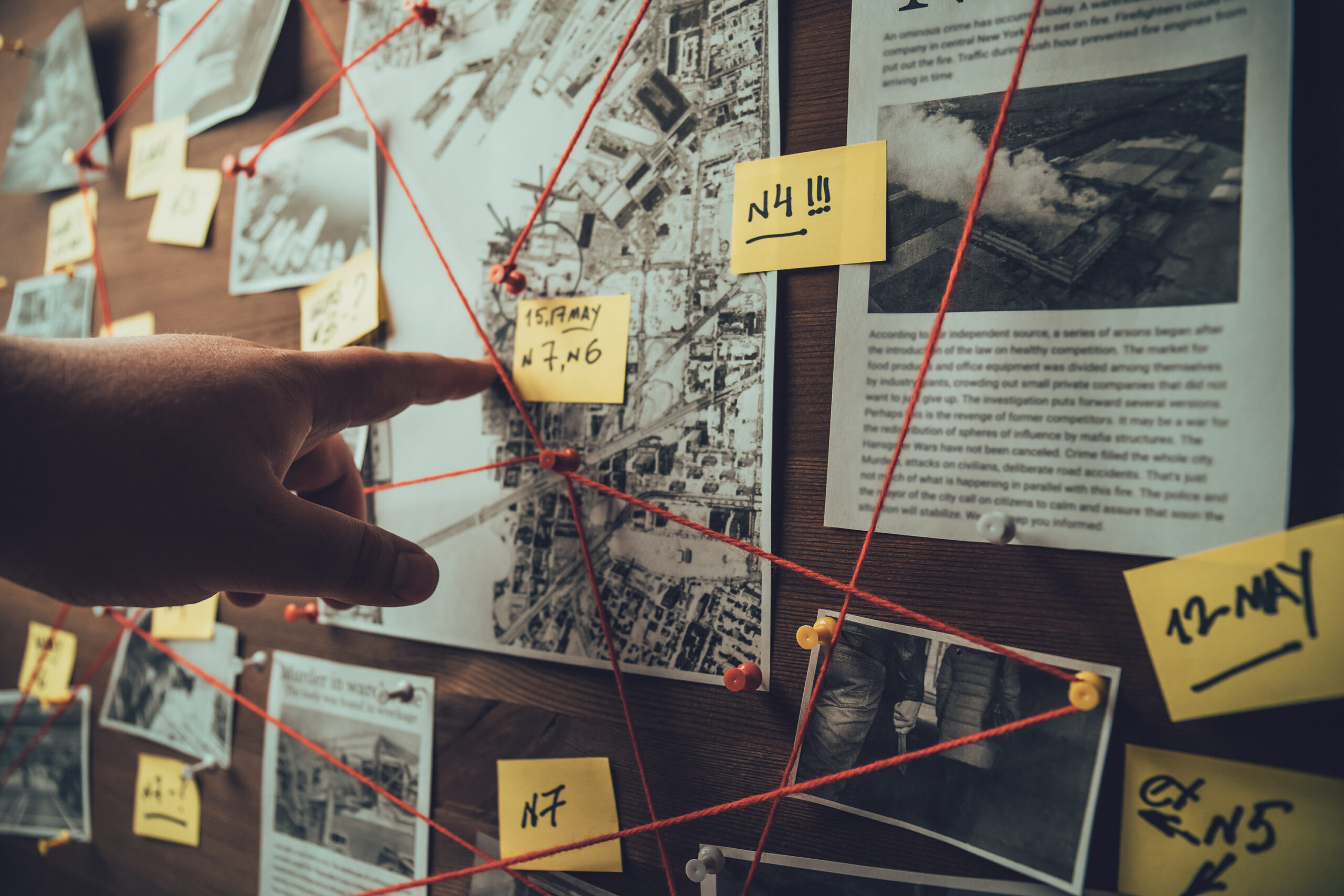 Tablero de detective con fotos de presuntos delincuentes, escenas del crimen y pruebas con hilos rojos, enfoque selectivo